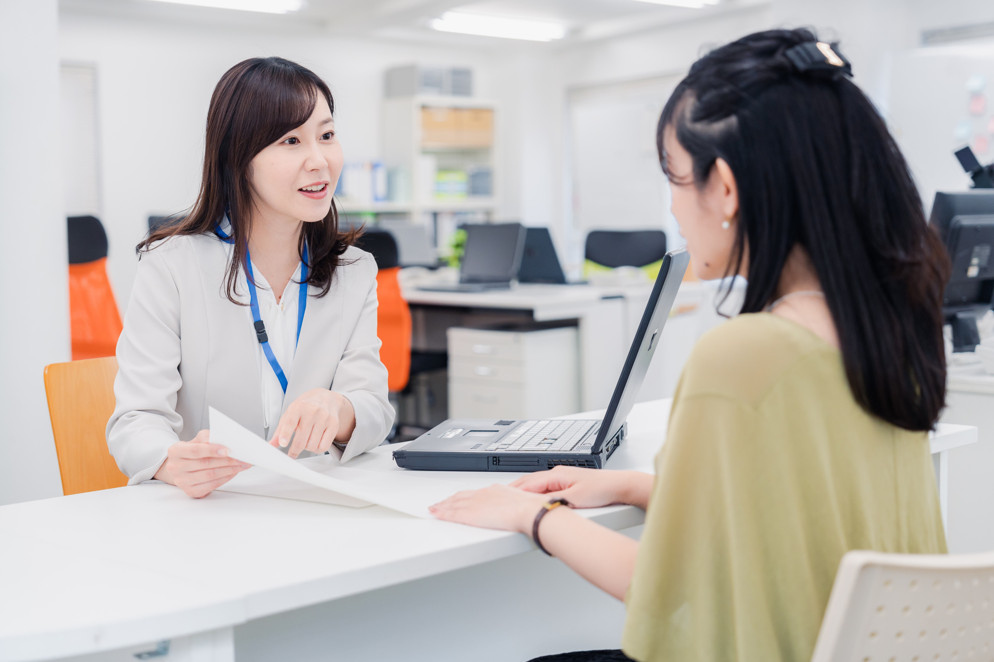 窓口で担当者から説明を受けながら相談する女性のイメージ
